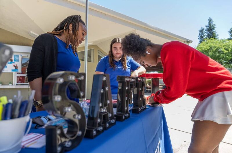 Latoya DeLong (left), a Member Engagement Specialist for SAFE Credit Union, helps Rancho Cordova High School student Justice Johnson Patterson (right) open a savings account as student Danielle Yeater (center) participates in the school’s personal finance program.