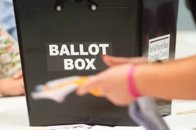 Ballot box and hand inserting a voting ballot.